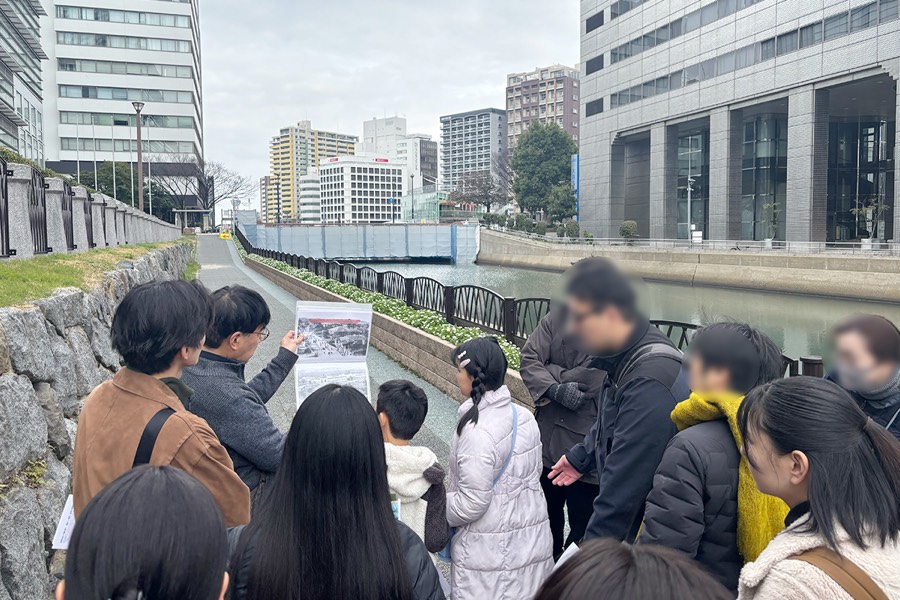 天神まちあるきで、川沿いに立ち昔の写真と今の街並みを見比べる参加者